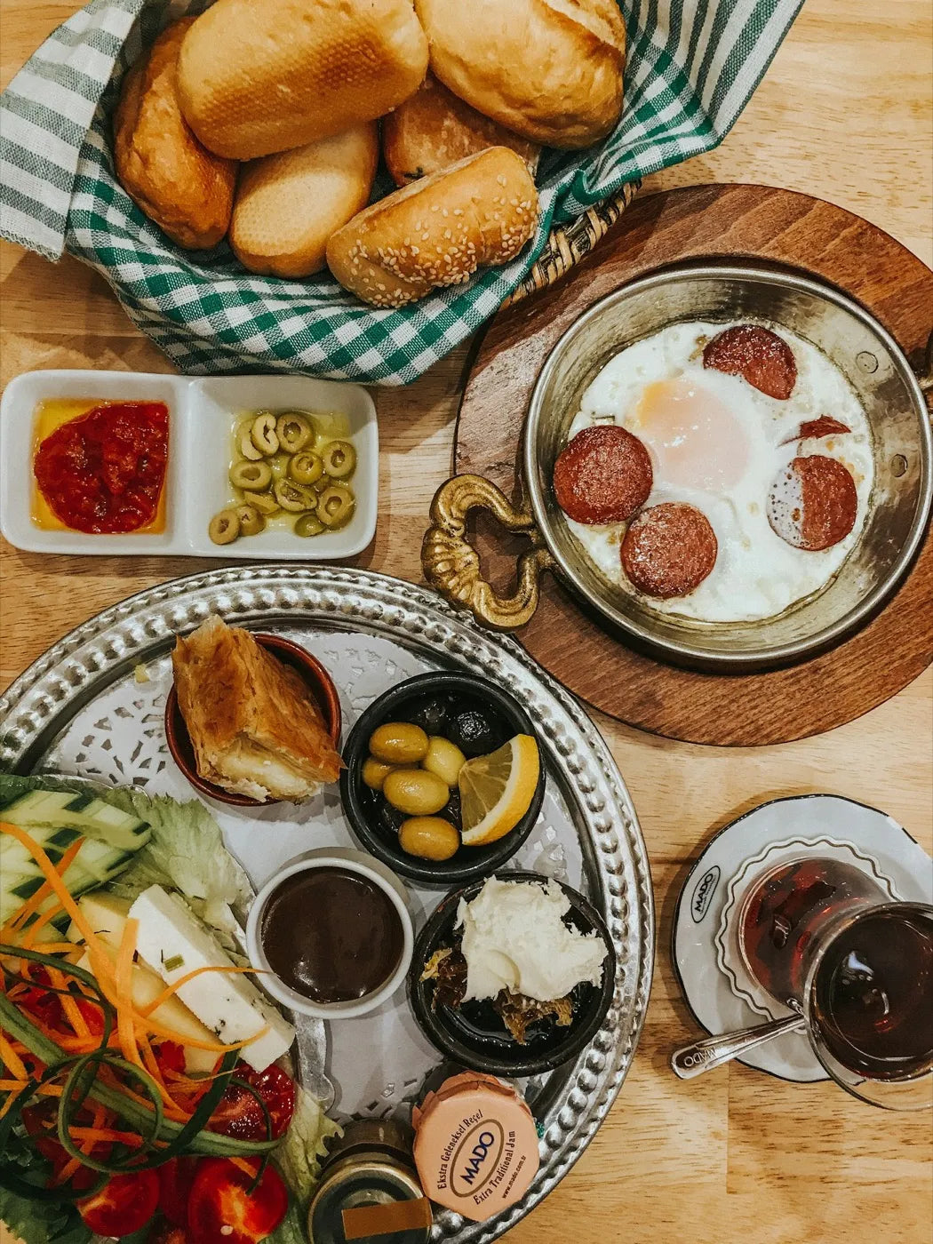 Turkish breakfast spread with a bread basket, olives, cheese, jam and tea